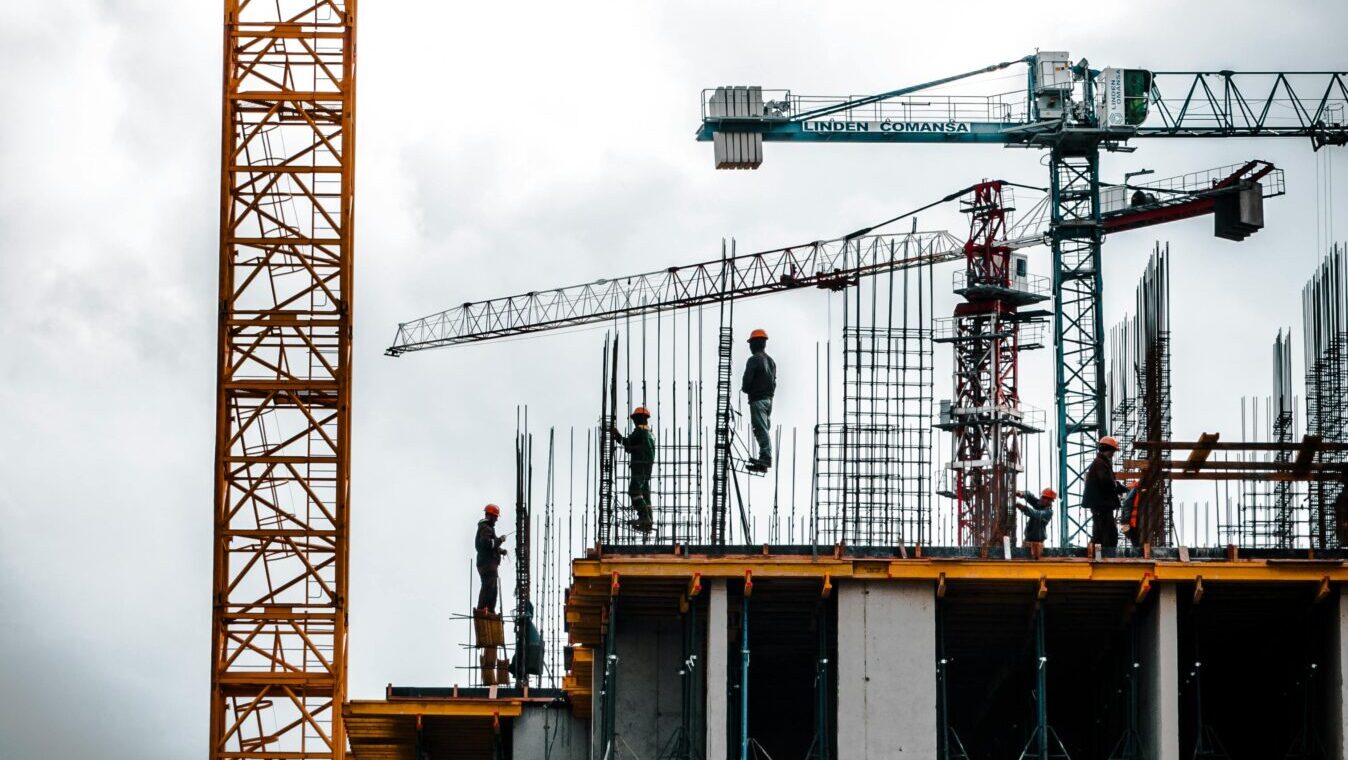 Vertical view of a construction site with cranes and workers building a skyscraper.